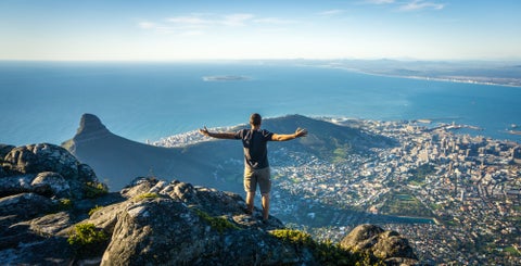 Tourist standing at the top of a mountain in Cape Town, South Africa, overlooking the city and coastline
