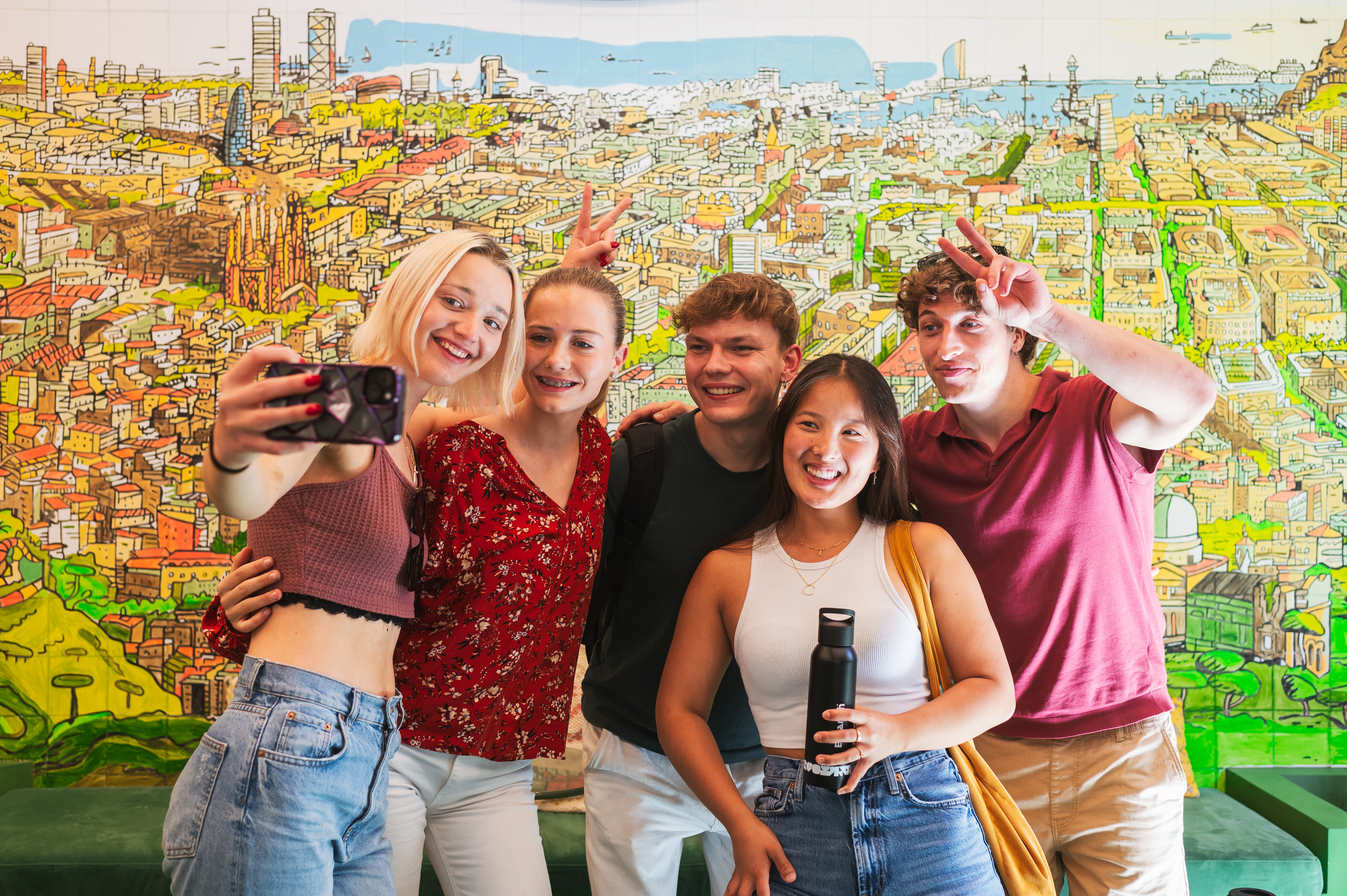 A group of students taking a selfie in front of the school mural