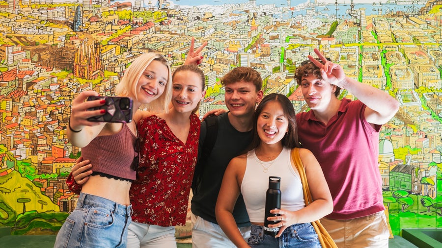 A group of students taking a selfie in front of the school mural