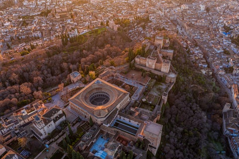 Aerial view of Alhambra fortress in Granada with Sierra Nevada mountains and whitewashed town below