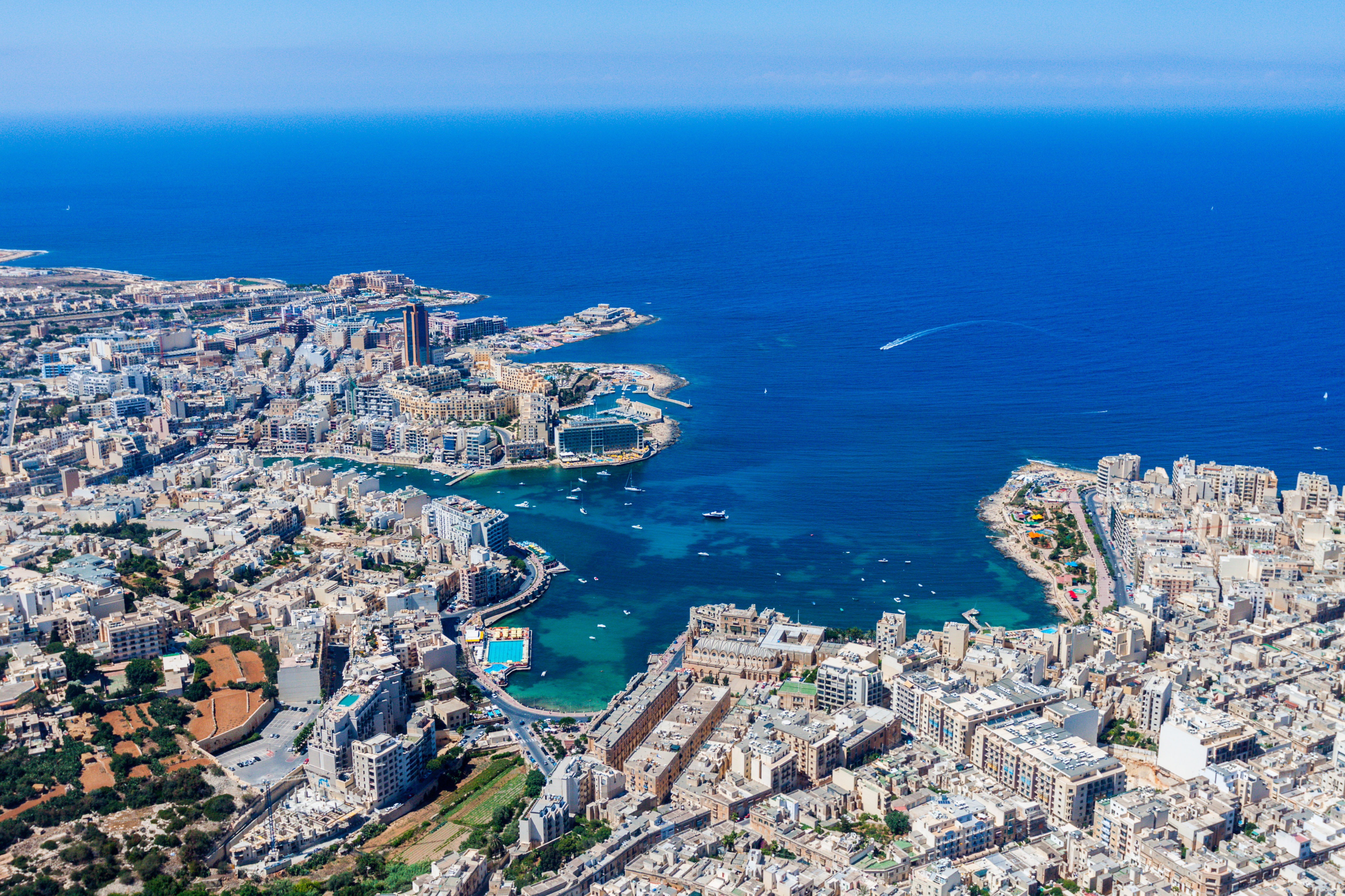 Aerial view of Malta showing St. Julian’s and Tas-Sliema, with St. Julian’s Bay, Balluta Bay, and Spinola Bay, along with harbours, coastline, and the Paceville skyscraper in the background
