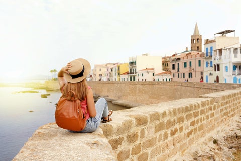 Tourist enjoying the view of Alghero Waterfront with historic buildings in Italy
