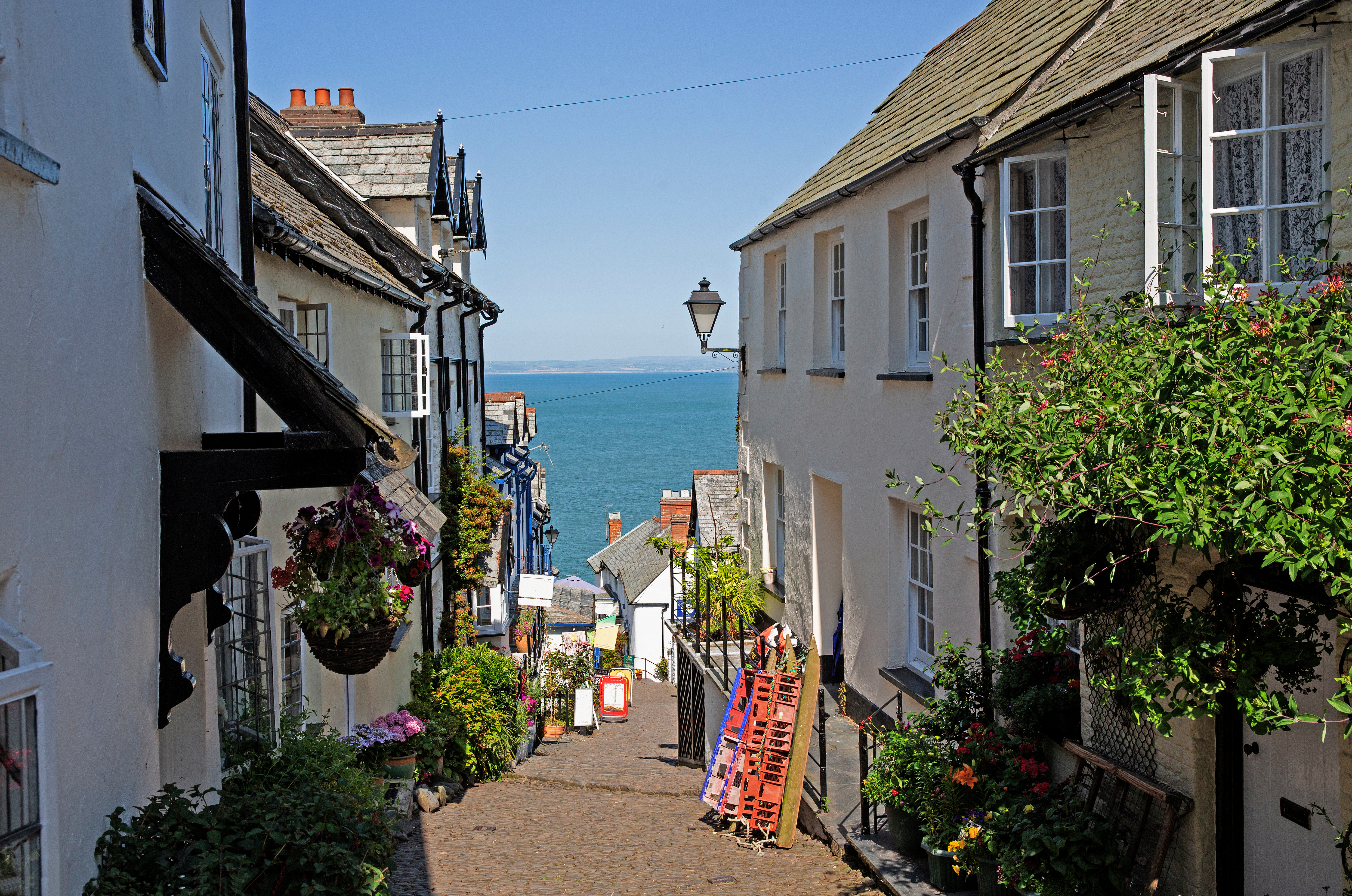 Street view in the city center of Devon, United Kingdom, featuring rows of white houses with the sea visible in the background