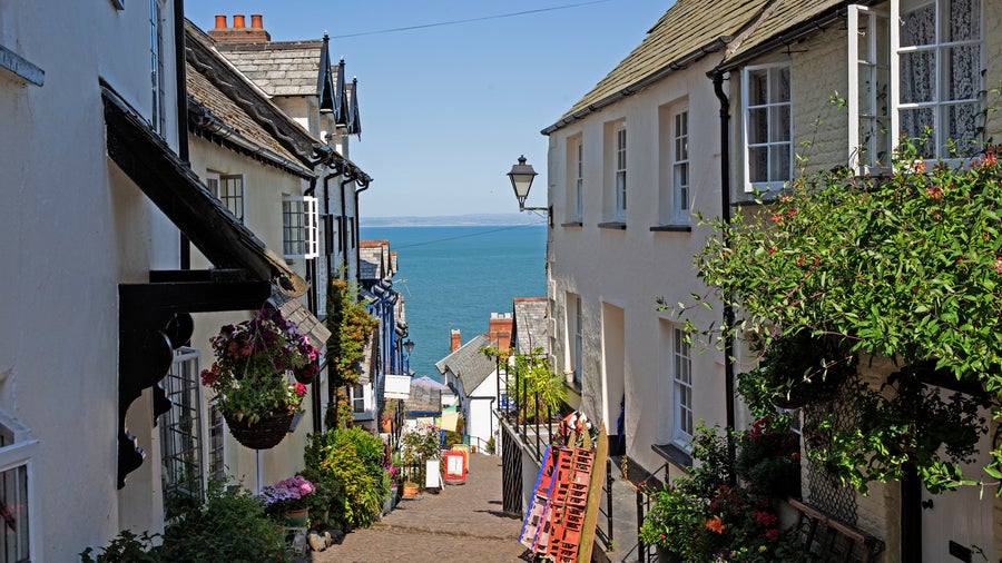Street view in the city center of Devon, United Kingdom, featuring rows of white houses with the sea visible in the background