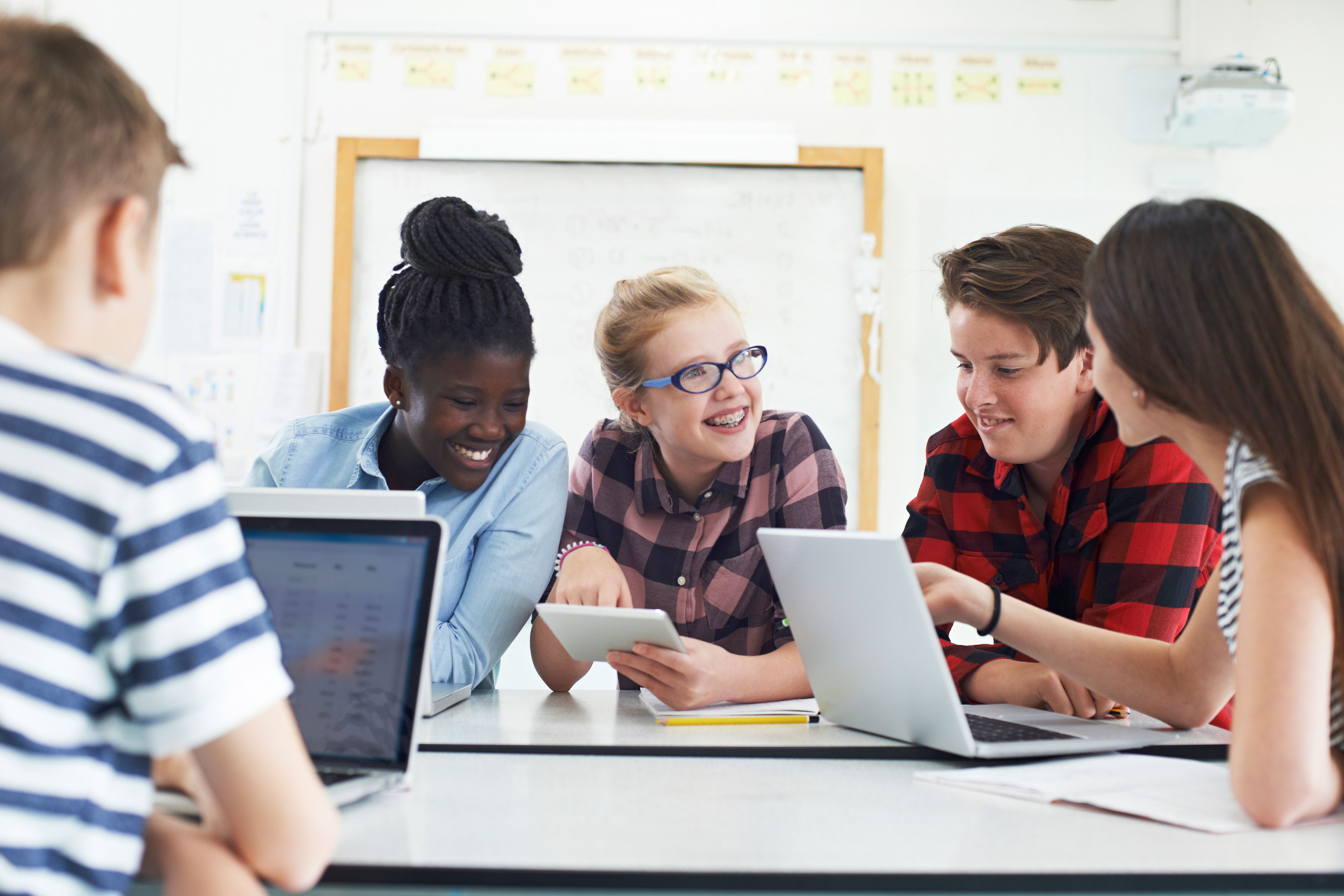 Young students in a classroom using laptops at their desks for digital learning and education