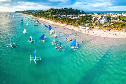 Crowds gathered on Boracay Island’s White Beach, Philippines, watching a vibrant sunset after the island’s recent reopening