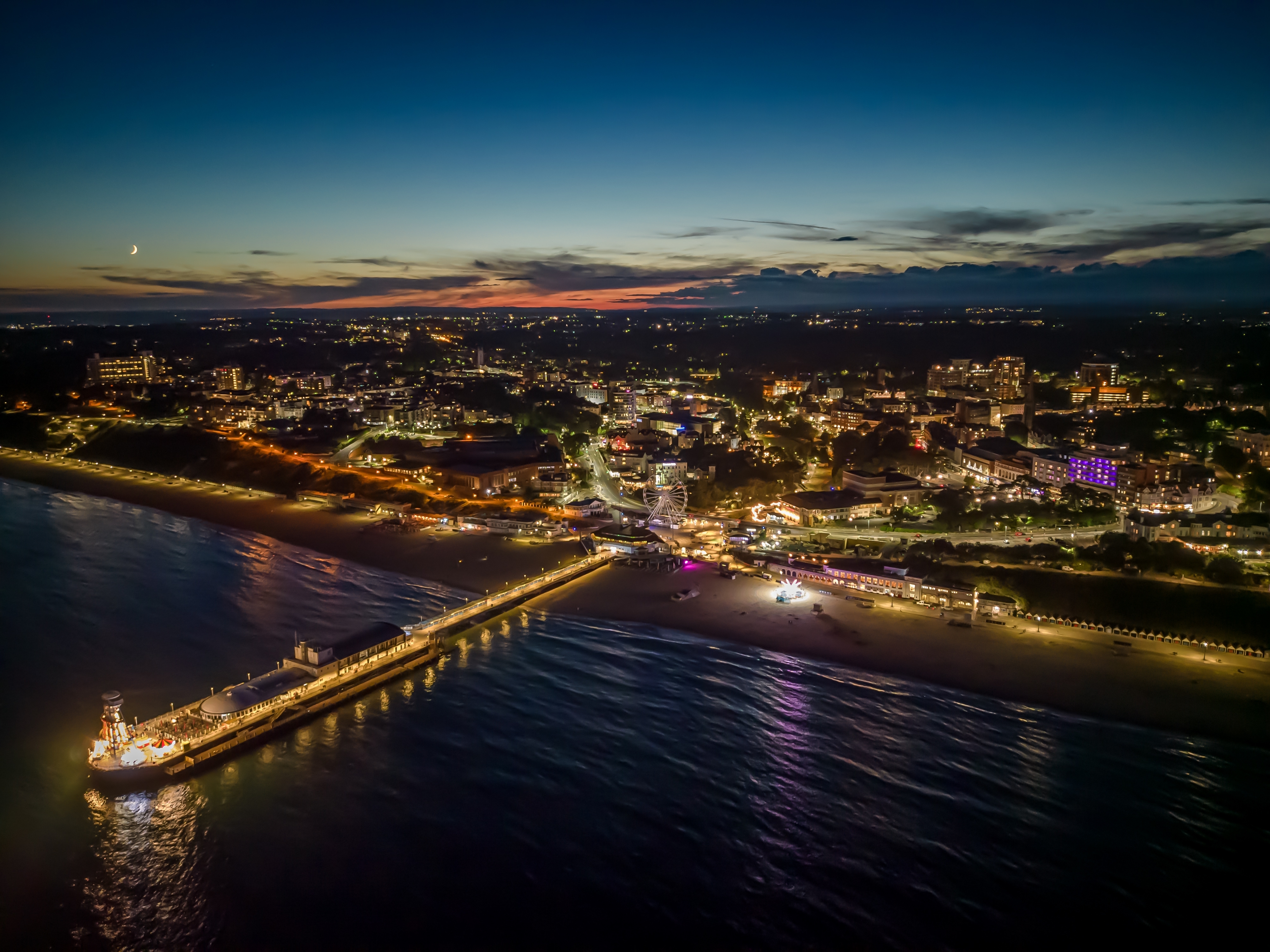 Illuminated Bournemouth Pier at night from above, stretching into the calm waters off the UK coast
