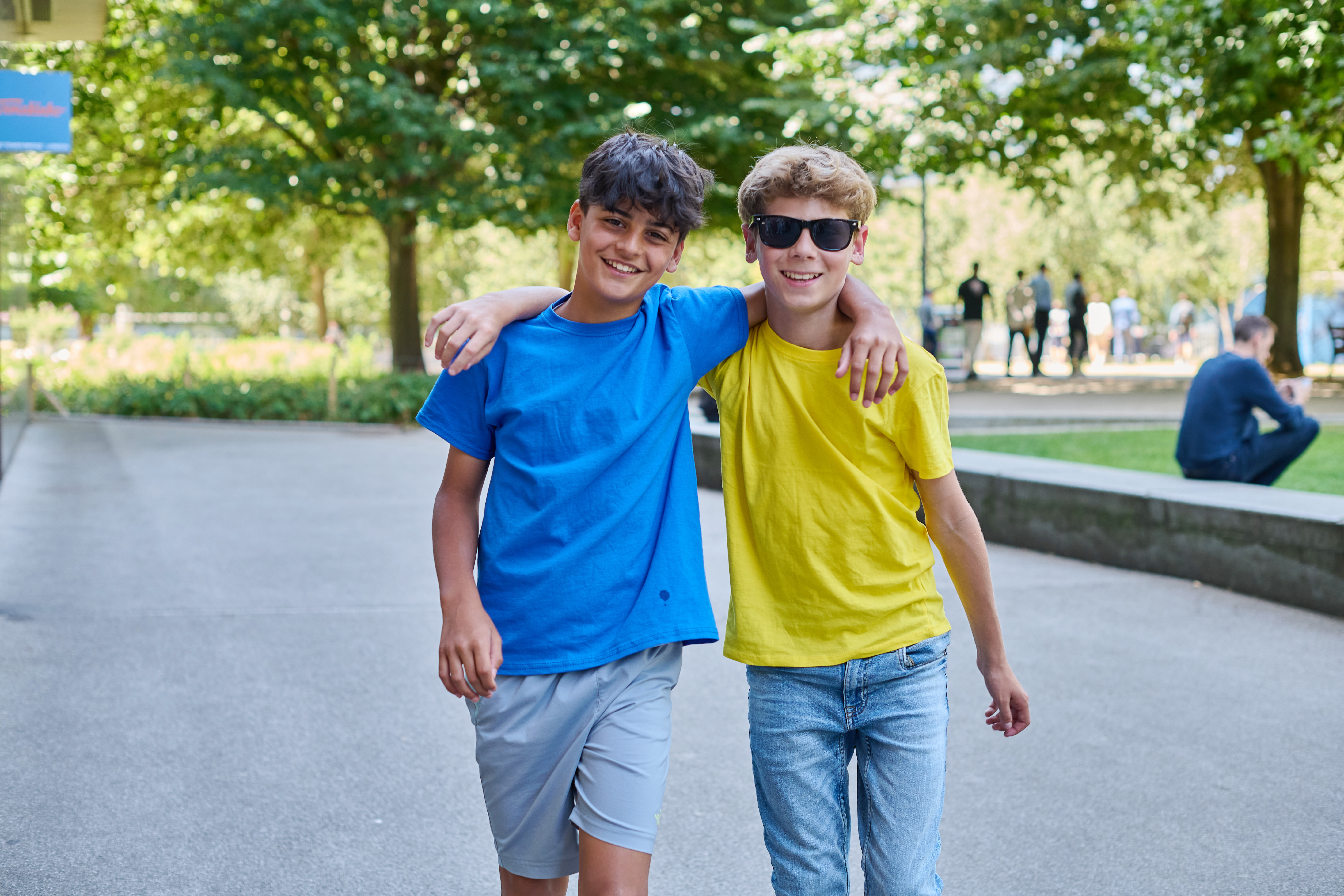 Two ESL boys holding each other posing in a London park on a sunny day