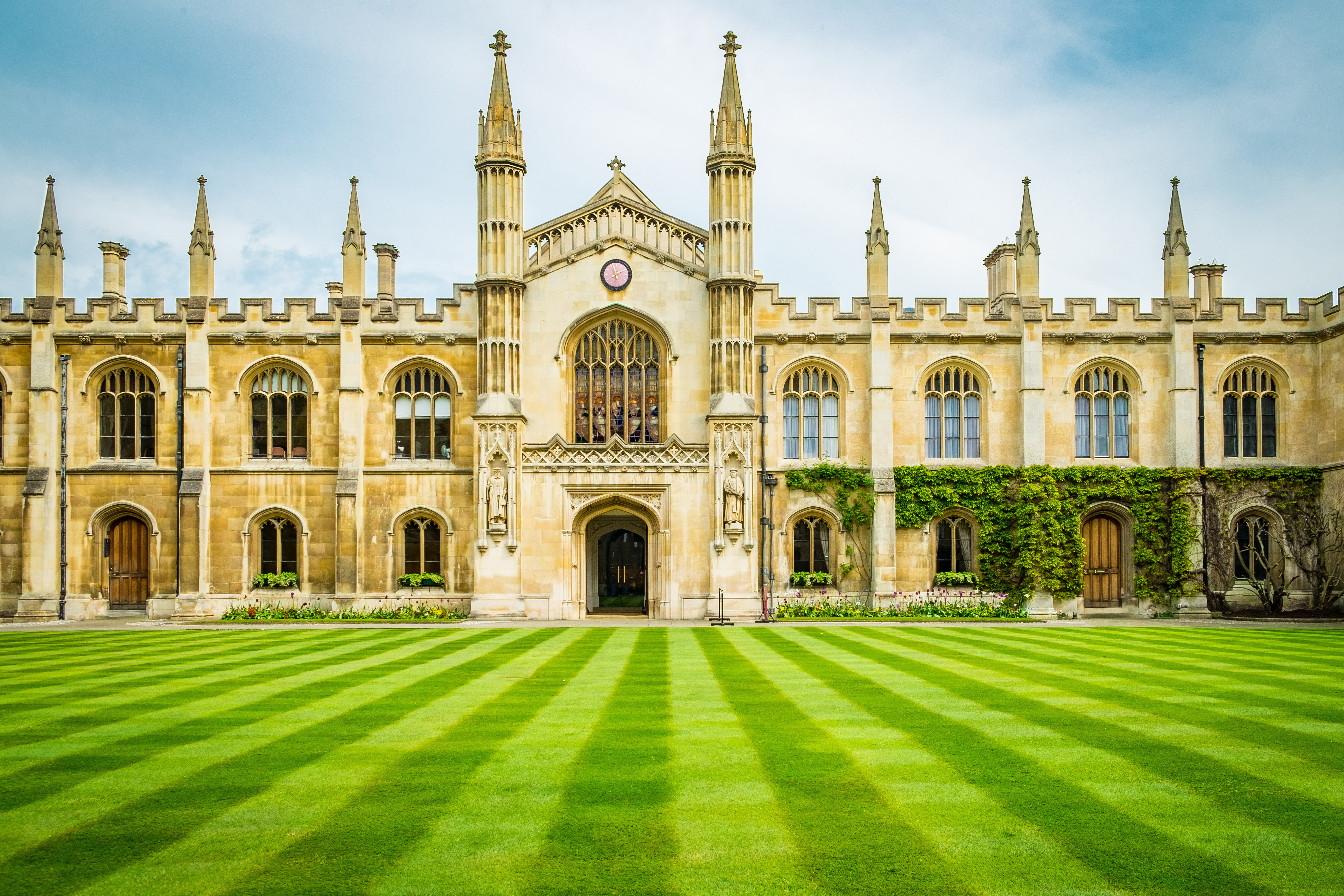 Front exterior view of Cambridge University building with green lawn in Cambridge, United Kingdom