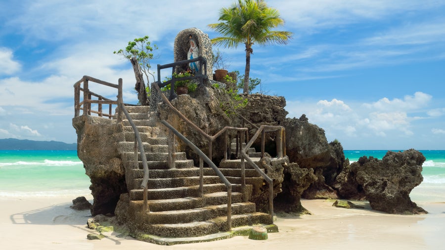 Willy’s Rock in Boracay, Philippines, featuring a statue of the Virgin Mary atop a volcanic formation on White Beach