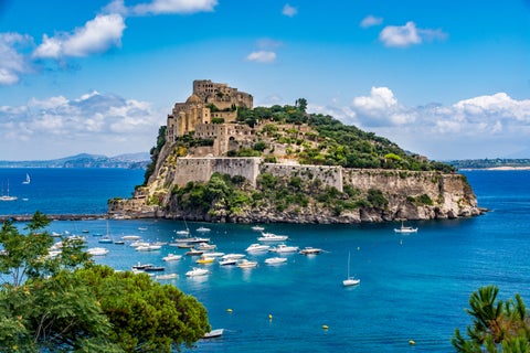 Aerial view of Tropea Island with its historic buildings surrounded by crystal blue ocean in Italy