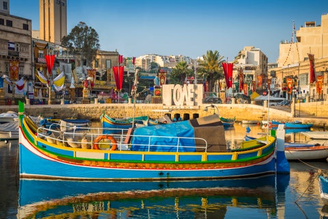 St. Julian's waterfront in Malta with boats anchored in the calm sea and coastal buildings lining the shore