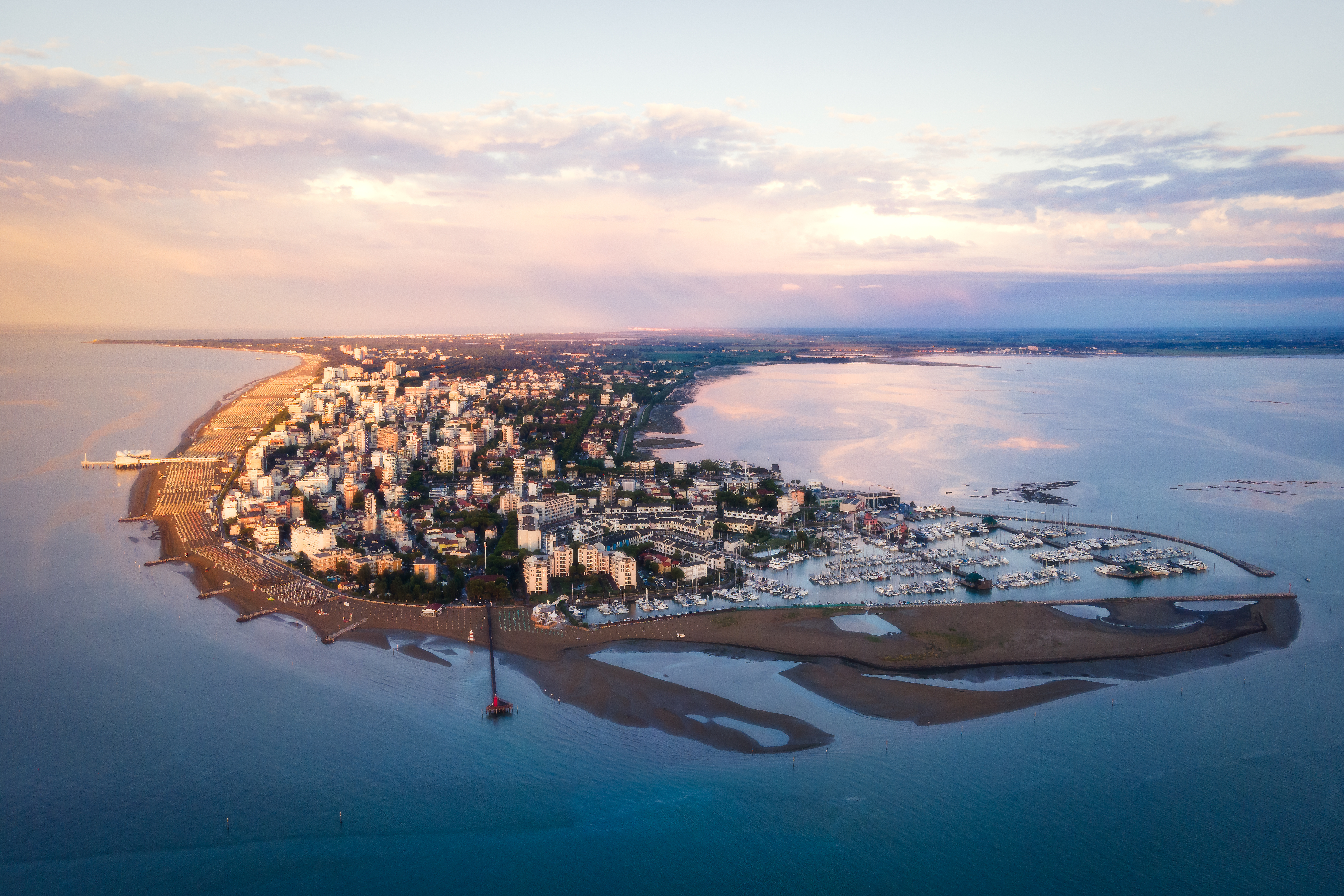 "Aerial view of Lignano, Italy, showing its coastline, beaches, and green urban areas