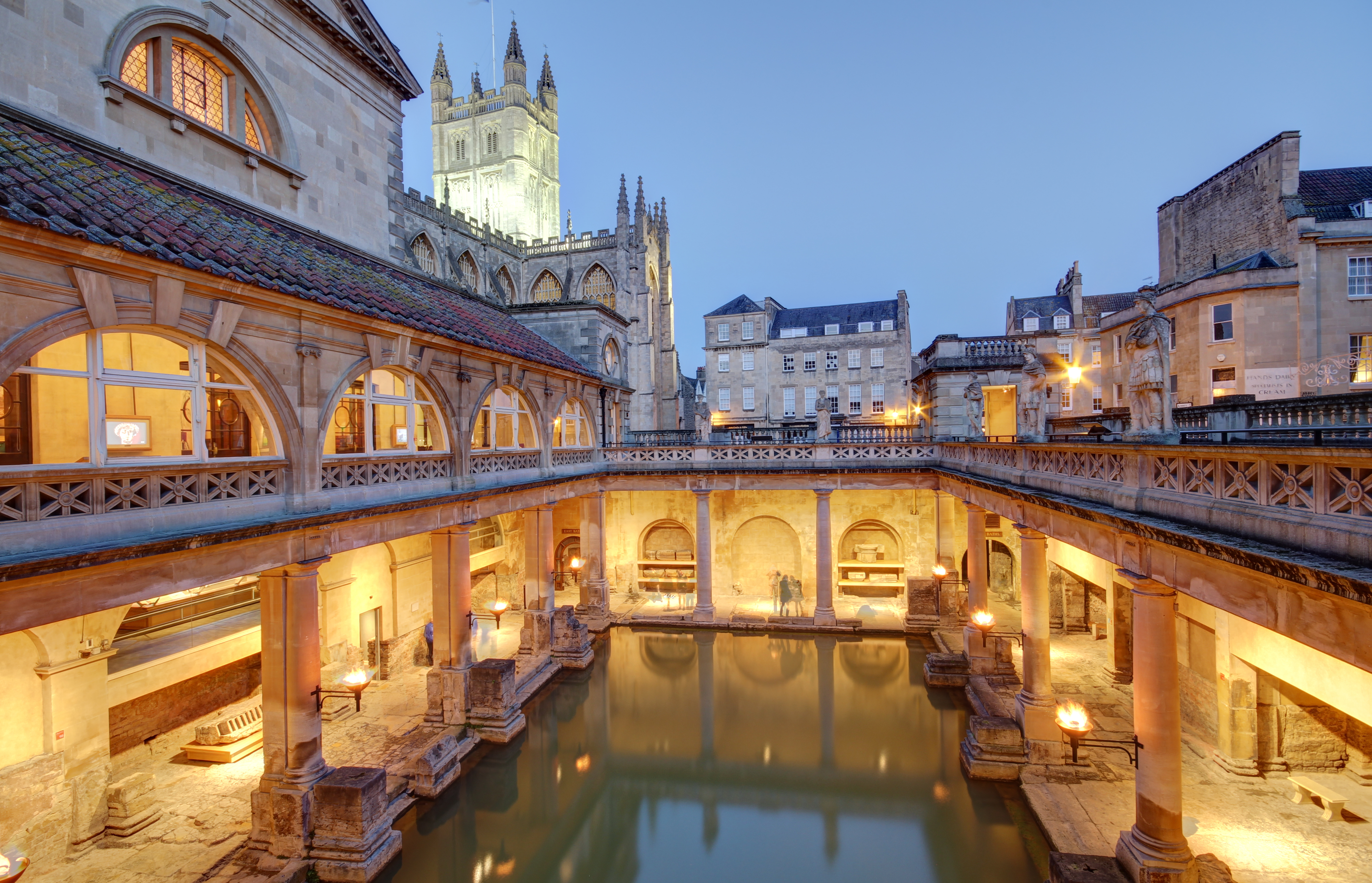 Roman Baths in Bath, UK illuminated by sunset light with glowing thermal waters