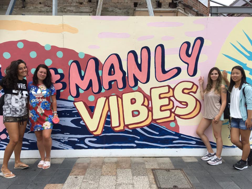 Four students in front of a mural