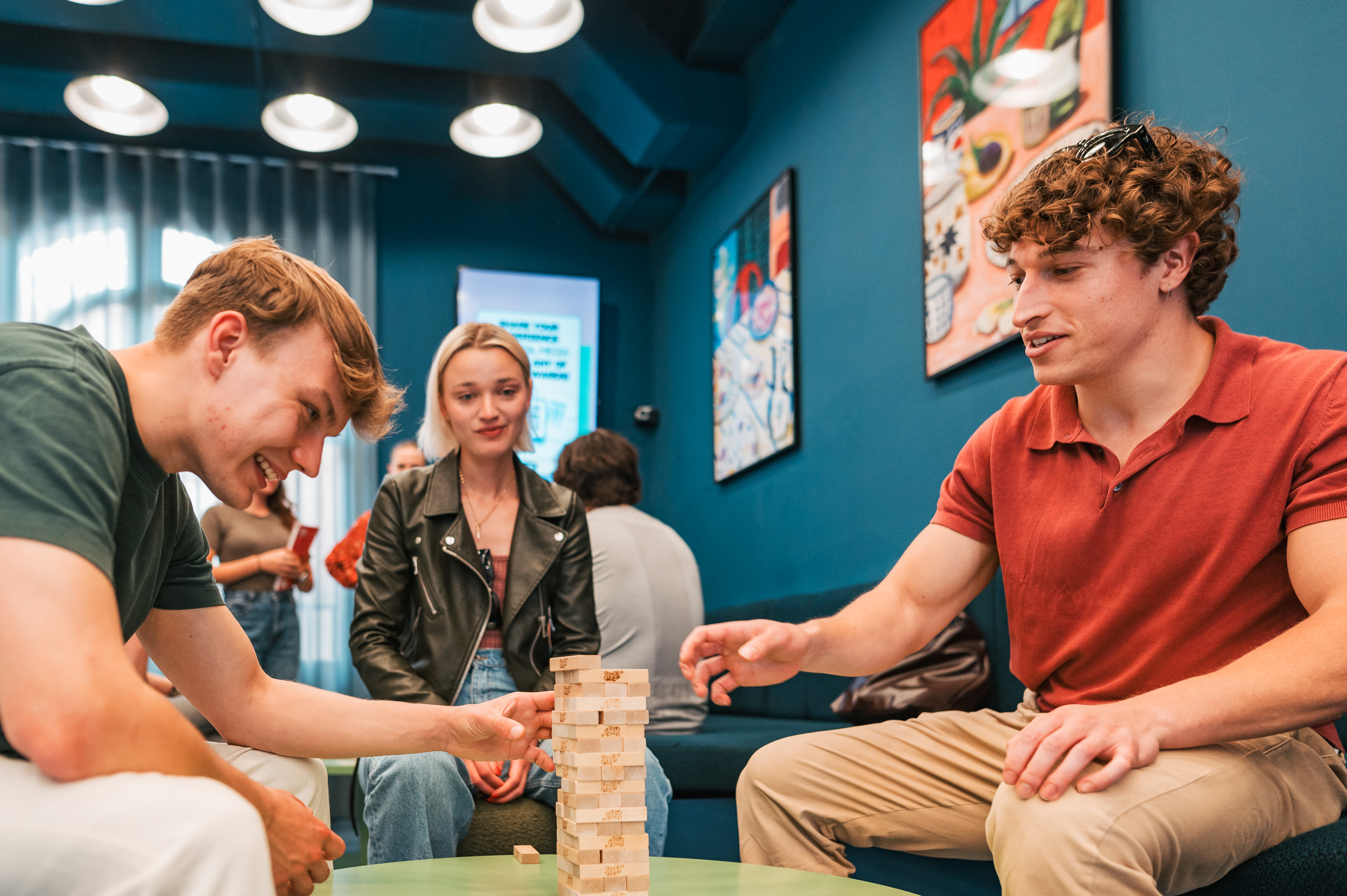 Three students playing Jenga in the common room