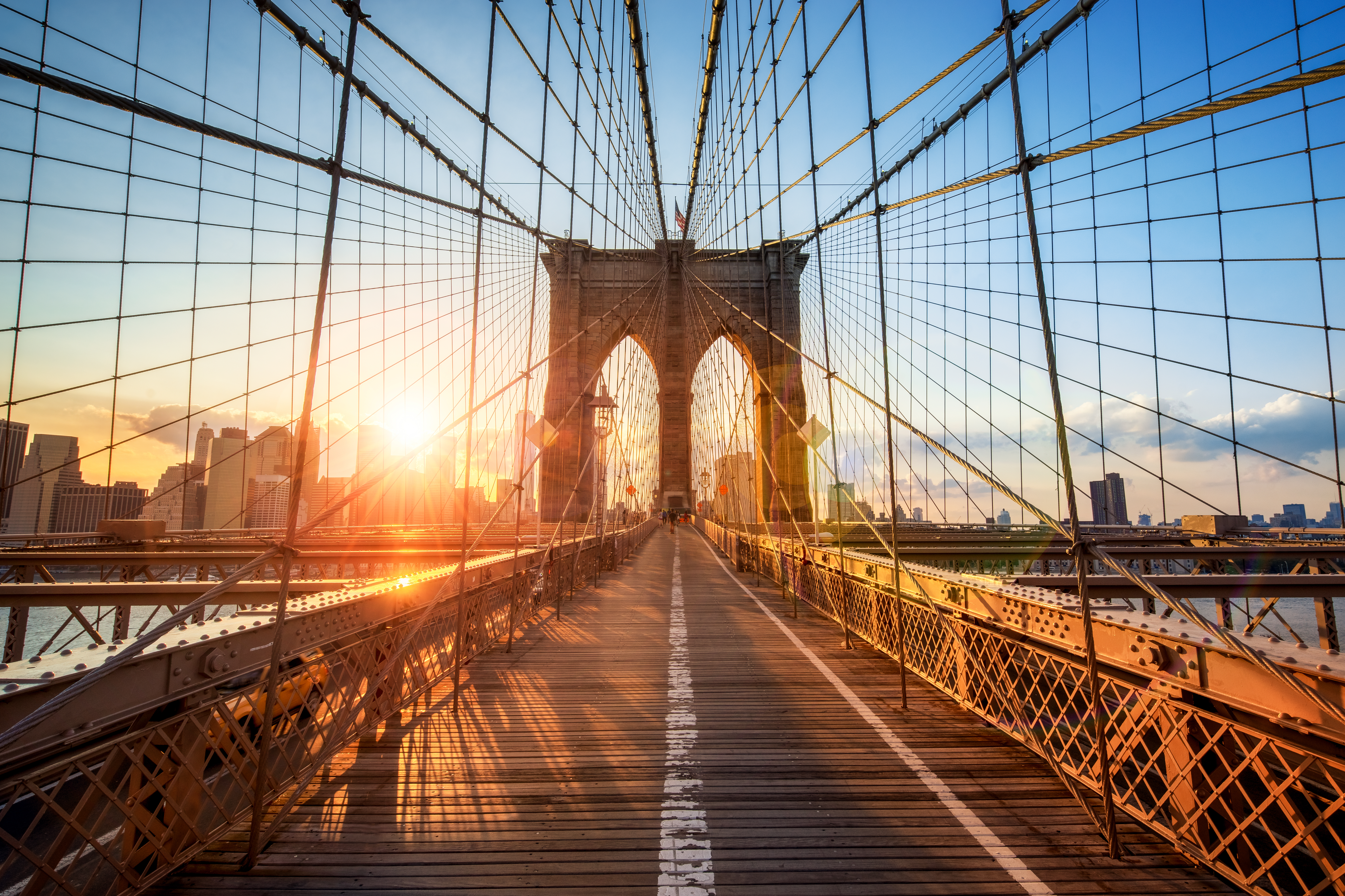 Inside view of Brooklyn Bridge at sunset with blue sky in Manhattan, New York City