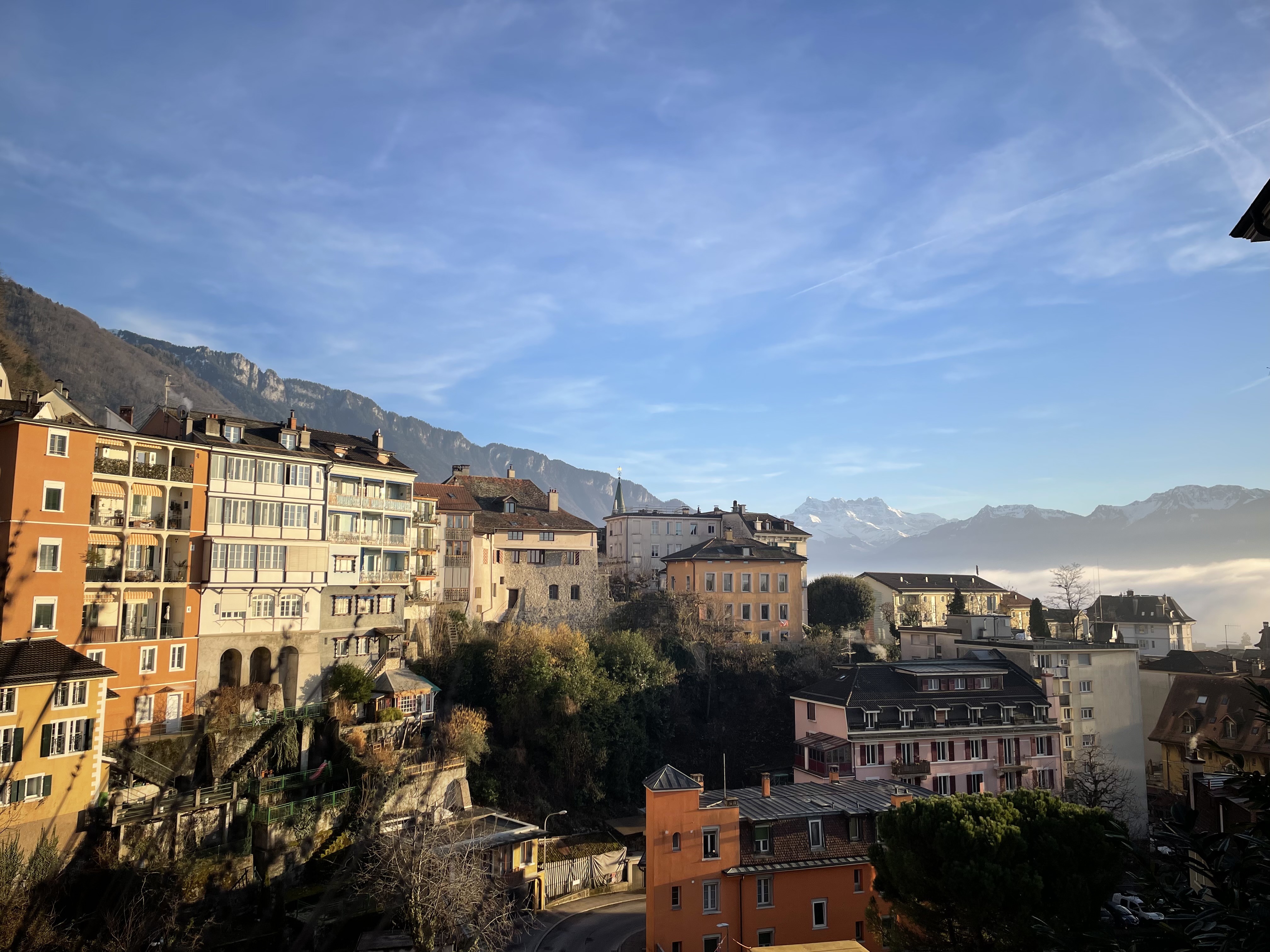 Vibrant colourful houses in Montreux, Switzerland, with the Swiss Alps towering in the background under a clear blue sky