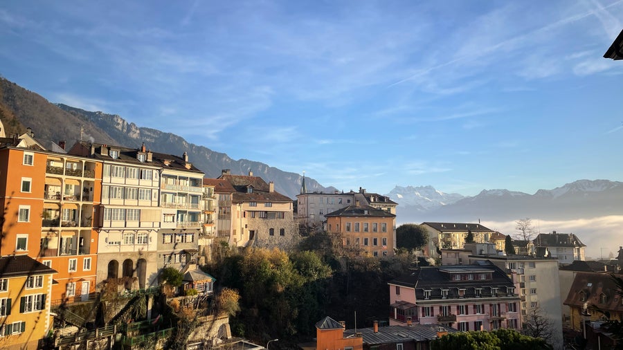 Vibrant colourful houses in Montreux, Switzerland, with the Swiss Alps towering in the background under a clear blue sky