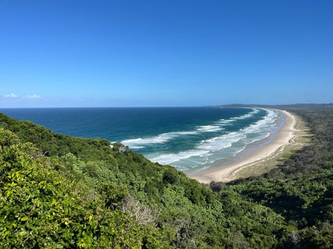 Aerial view of Byron Bay surrounded by lush greenery and overlooking the turquoise waters of the Pacific Ocean