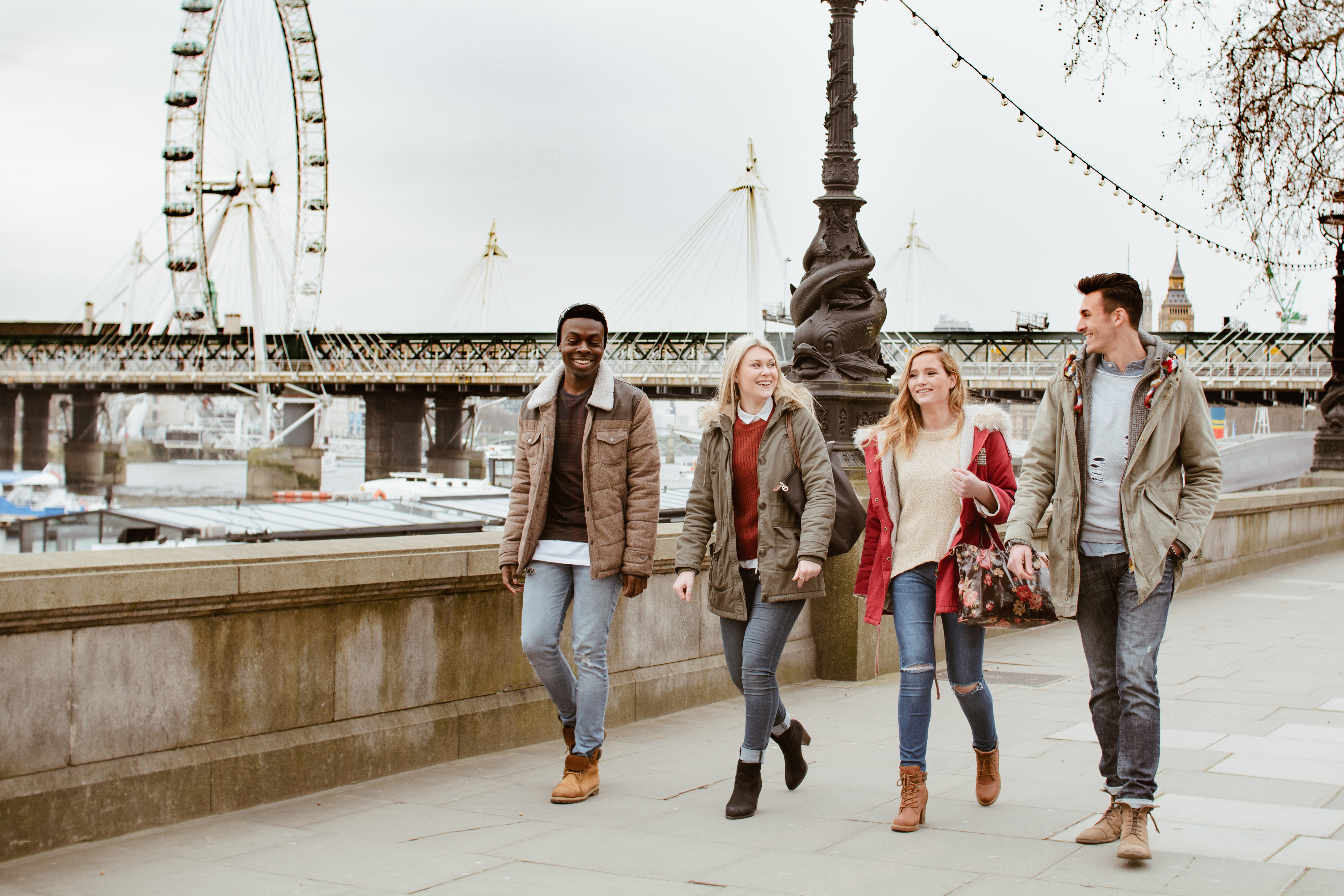 International students walking by the River Thames with the London Eye in the background on a cloudy day
