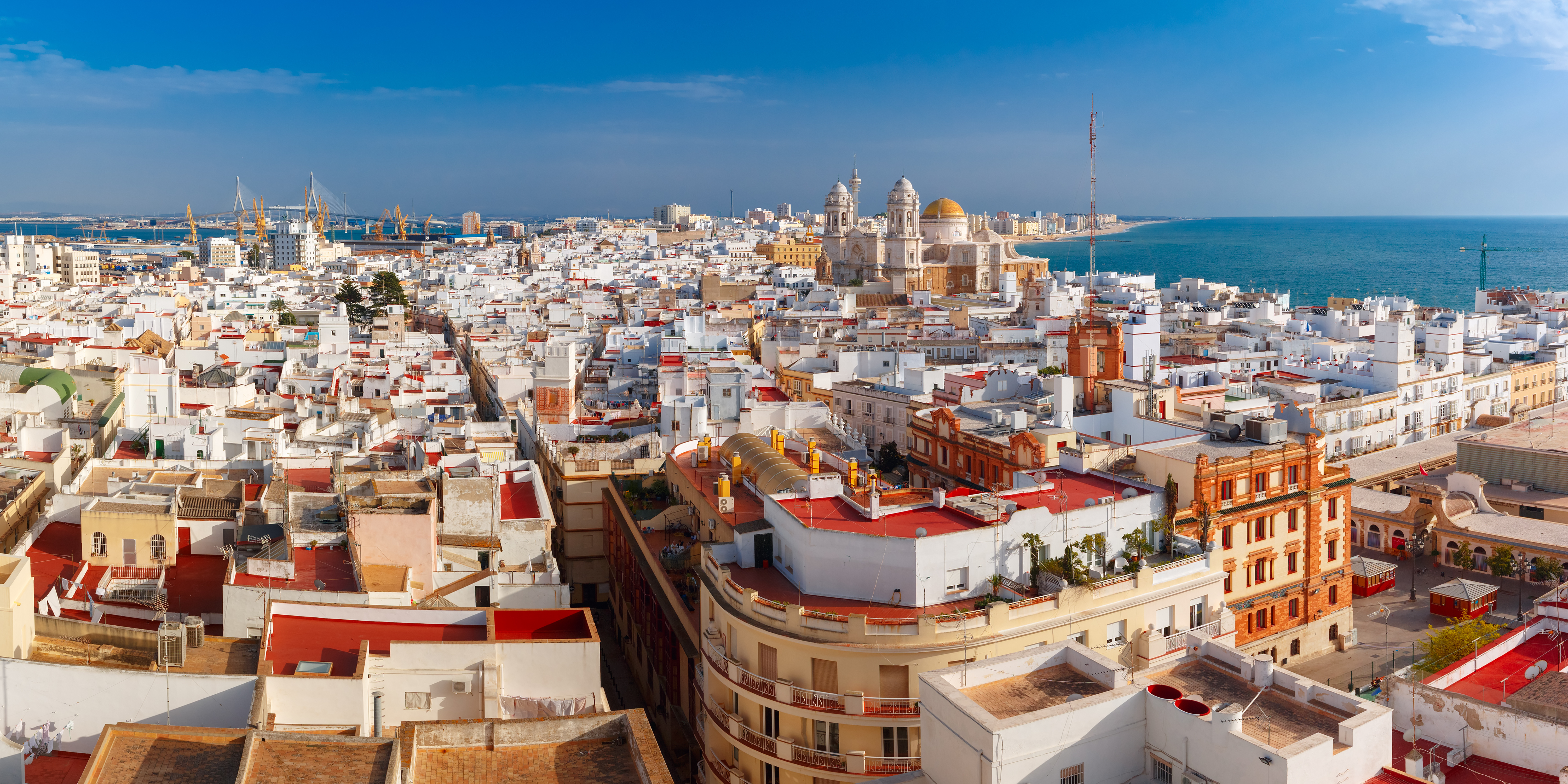 Aerial panoramic view of Cádiz, Spain, with morning light illuminating the old city rooftops and the Cathedral de Santa Cruz, seen from Torre Tavira