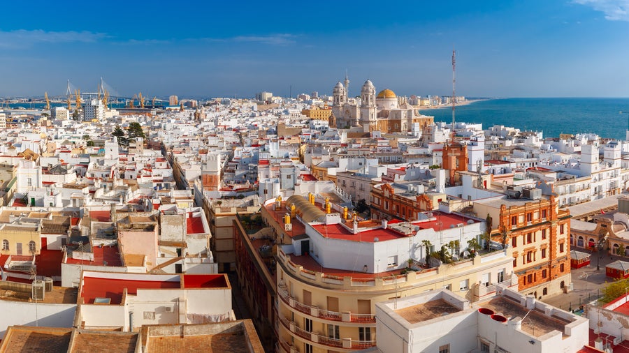 Aerial panoramic view of Cádiz, Spain, with morning light illuminating the old city rooftops and the Cathedral de Santa Cruz, seen from Torre Tavira