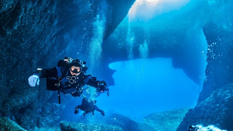 Scuba diving in the clear waters of Salina Bay, Malta, with rocky seabed and marine life visible below