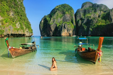 Tourist posing for a picture at the Beach in Phuket, Thailand, with sandy shore and mountains in the background