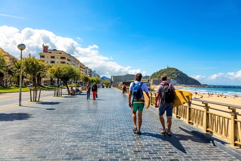Tourists walking along the seaside promenade in San Sebastián, Spain, with views of the beach and ocean