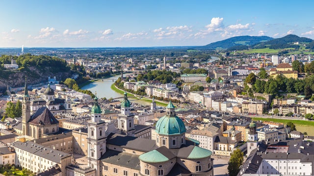 Hohensalzburg Fortress, and the Salzach River, all set against a backdrop of picturesque Alpine mountains in Salzburg, Austria