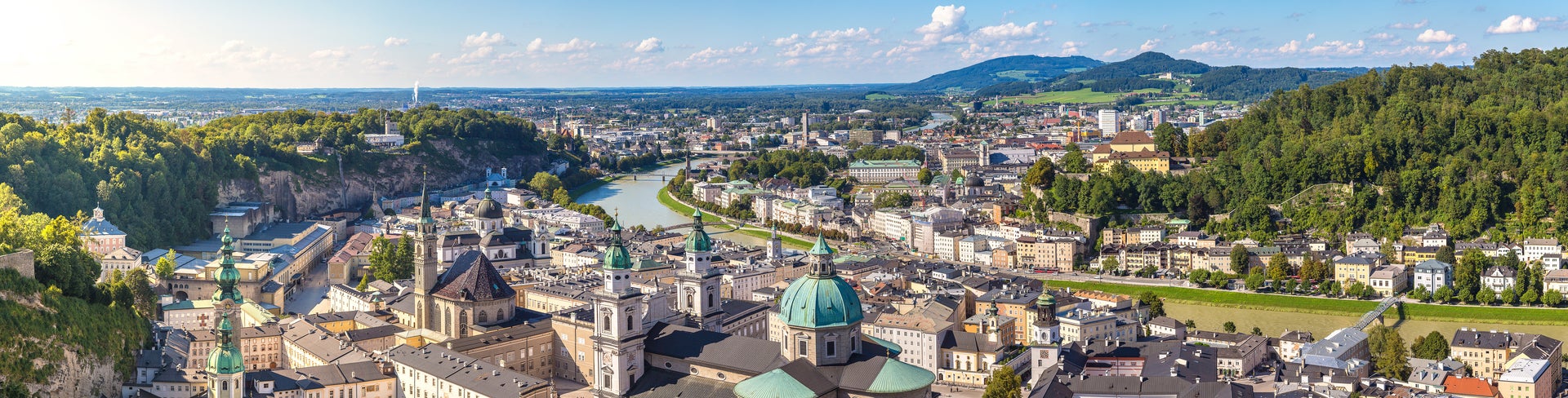 Hohensalzburg Fortress, and the Salzach River, all set against a backdrop of picturesque Alpine mountains in Salzburg, Austria