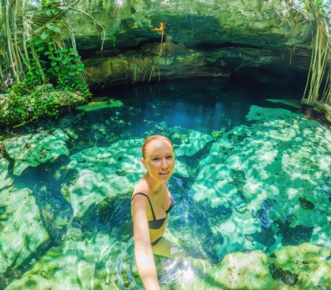 Tourist swimming in the crystal-clear waters of a cenote pond at Playa del Carmen, Mexico