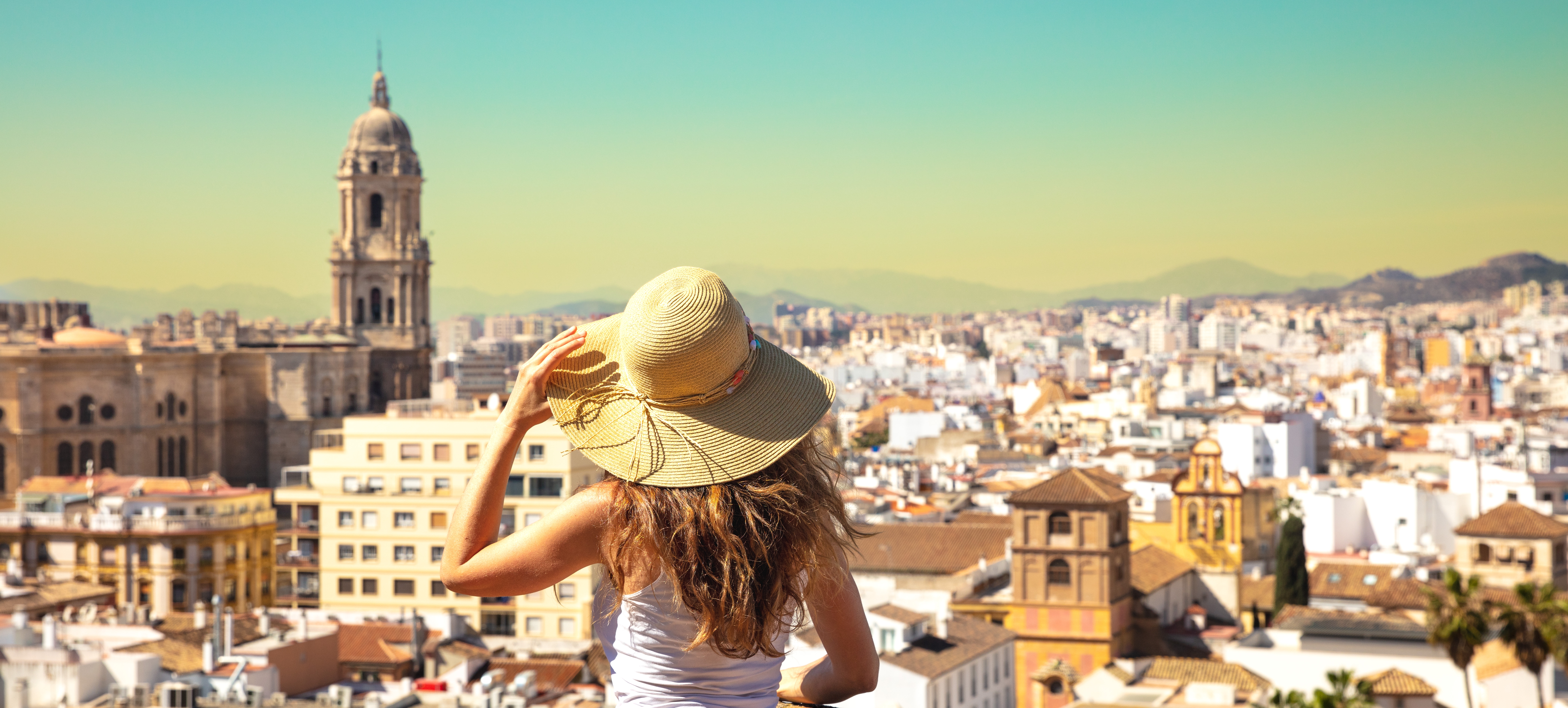 Tourist girl wearing a sun hat looking out over Málaga, Spain, from a scenic overlook