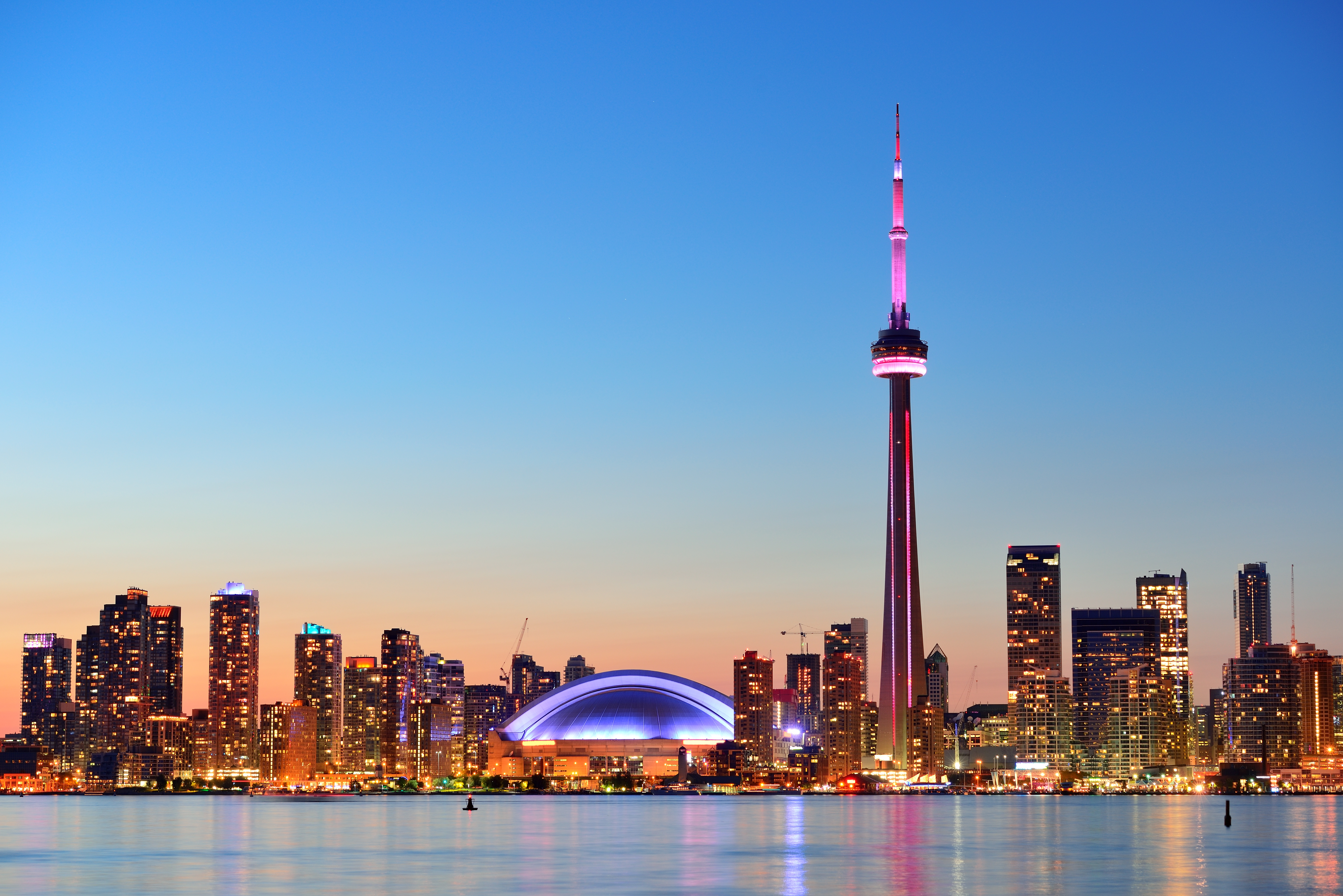 Toronto skyline at sunset with the illuminated CN Tower and city waterfront along Lake Ontario, Canada