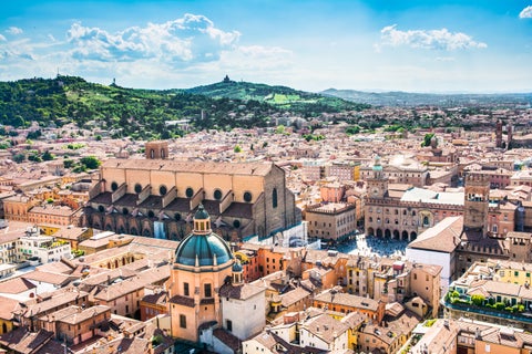 Aerial view of Bologna with its iconic medieval towers, including the Asinelli and Garisenda, rising above the city's red-tiled rooftops