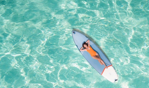 Woman relaxing on a surfboard in the clear waters of Boracay Island, Philippines
