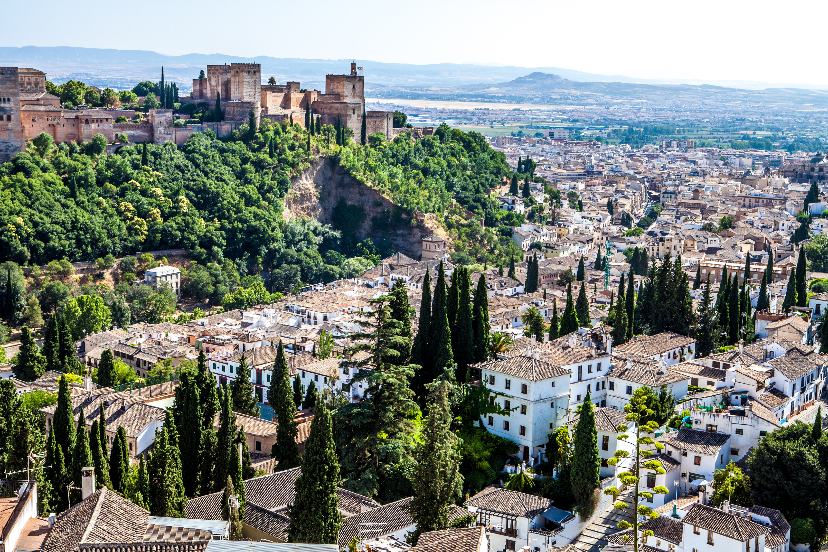 Granada, Spain with the Alhambra's majestic architecture perched on a hill, framed by the Sierra Nevada mountains, showcasing the city's historic charm