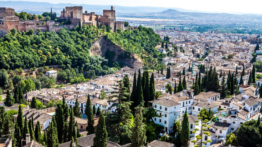 Granada, Spain with the Alhambra's majestic architecture perched on a hill, framed by the Sierra Nevada mountains, showcasing the city's historic charm
