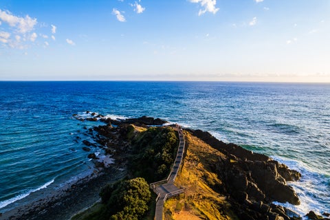 Aerial view of Byron Bay surrounded by lush greenery and overlooking the turquoise waters of the Pacific Ocean