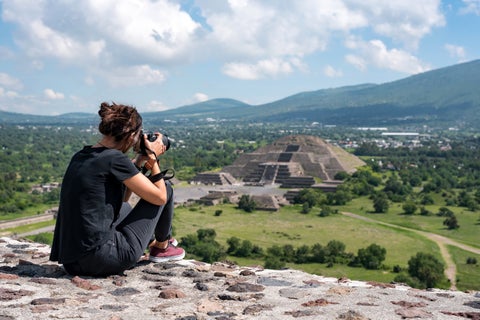 Tourist standing atop the Pyramid of the Sun in Teotihuacan near Mexico City, Mexico, overlooking ancient ruins and surrounding valley