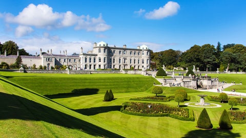 Elegant white historic building with classic architectural features, accompanied by a long, manicured garden in front, set against the picturesque backdrop of Bray, Ireland