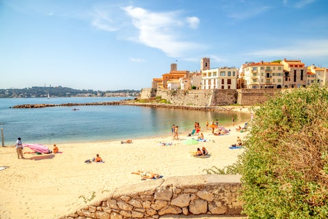 White-sand Beach with plain sea with historic buildings at Antibes, France