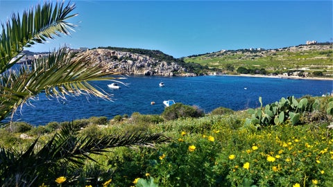 St. Paul’s Bay, Malta, with boats floating in the calm blue sea and coastline in the background