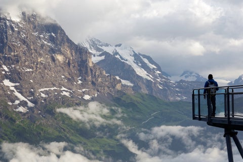 Tourist enjoying panoramic mountain viewpoint near Zurich, Switzerland, overlooking the city and surrounding Swiss Alps