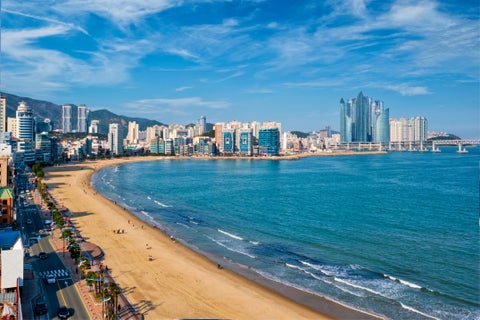 Gwangalli Beach in Busan, South Korea, with sandy shoreline, clear waters, and Gwangan Bridge in the background