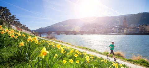 Girl running next to Neckar River with Heidelberg Castle and Old Bridge in Heidelberg, Germany