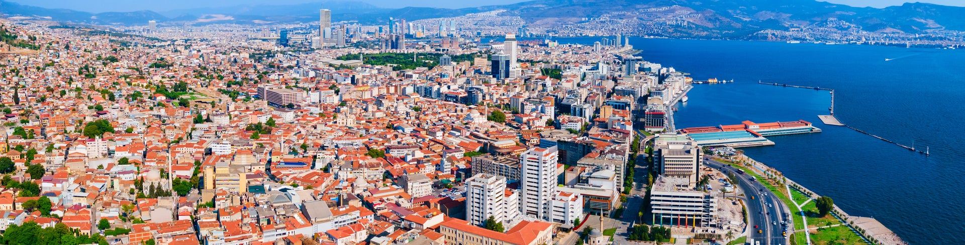 Aerial view of Izmir, Turkey, showing modern cityscape along the Aegean Sea shoreline with the historic Asansör Elevator, Konak Square, and Clock Tower