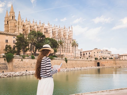 Tourist in Palma de Mallorca, Spain, standing near La Seu Cathedral with Parc de la Mar lake beside the historic building