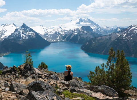 Tourist enjoying panoramic view from snowy mountain peak overlooking Garibaldi Lake in Whistler, Canada, an outdoor adventure and travel destination